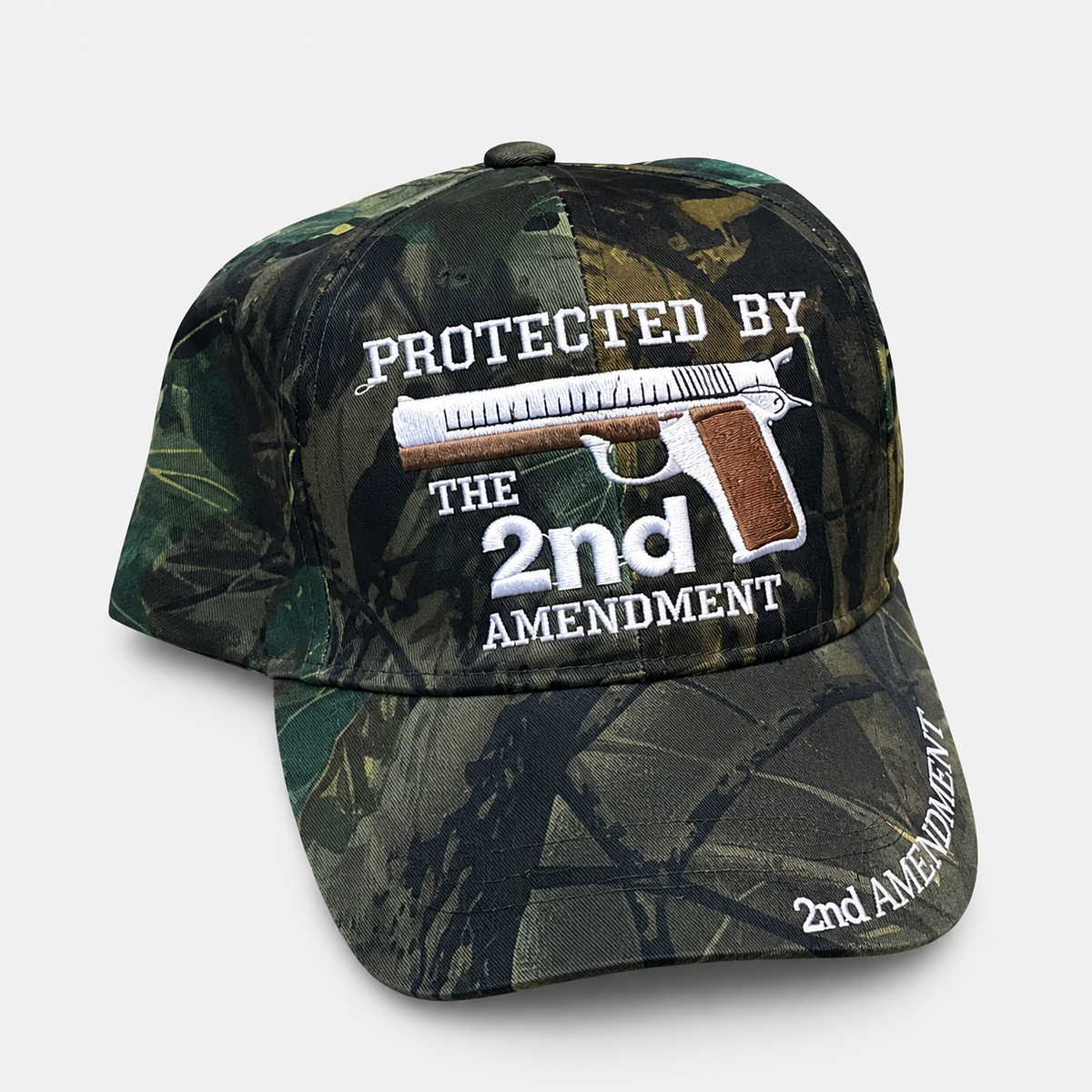 Dark woodland camouflage cap with Protected by the 2nd Amendment embroidery and a pistol emblem