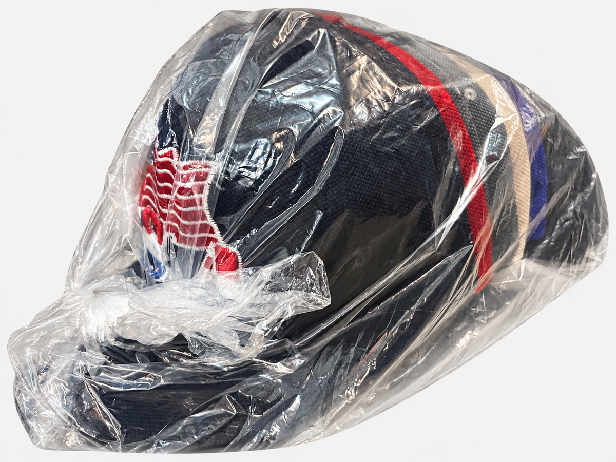 Side view of USA flag eagle-brim caps in clear dozen packaging on a light gray background