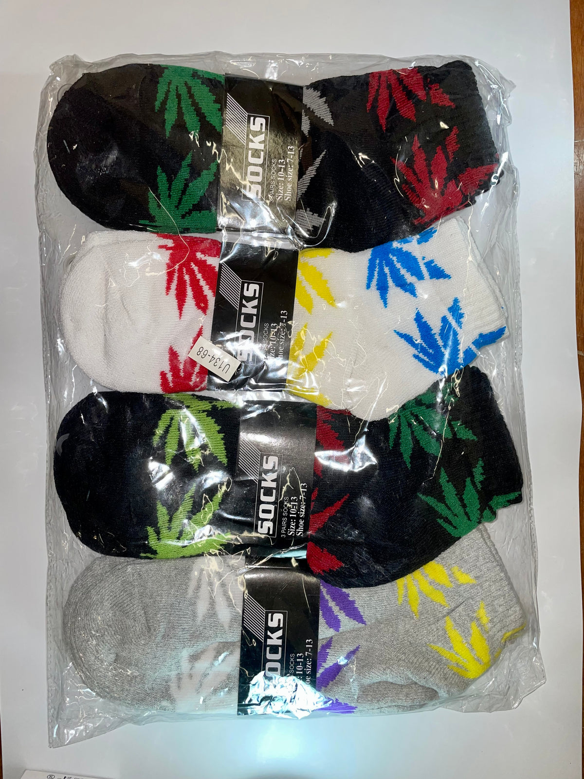 Men’s ankle socks with multicolored leaf designs in clear packaging